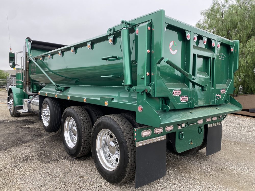 The same green dump body from the opposite rear quarter
