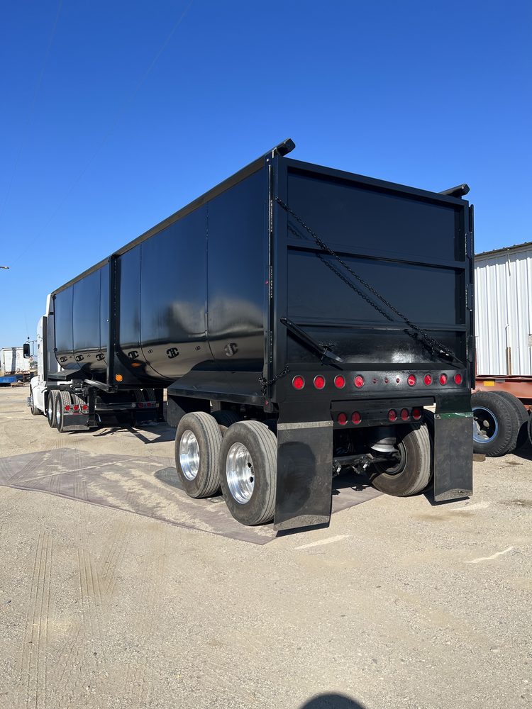 Black end dump trailer, rear three quarter view