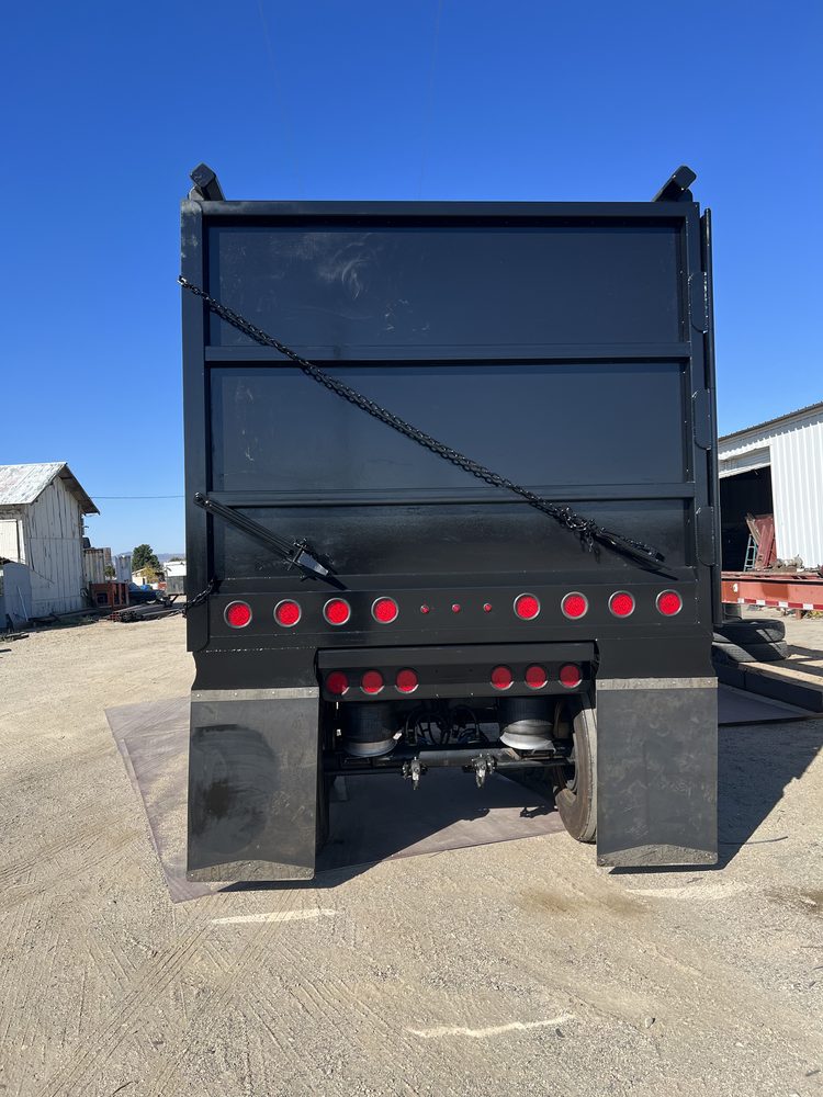 Black end dump trailer photographed square from the rear