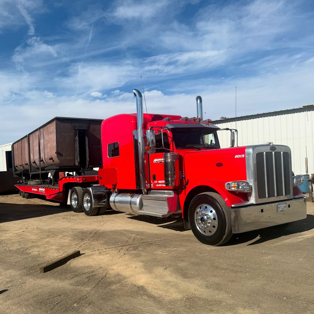 Red tractor coupled to a black end dump trailer