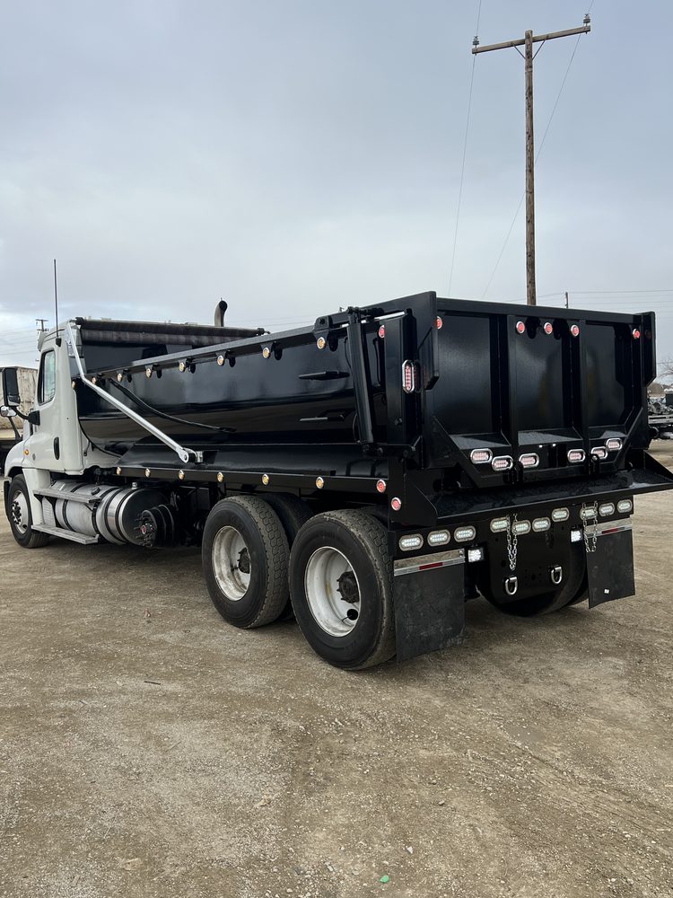 Black dump body mounted on a white chassis, rear three quarter view