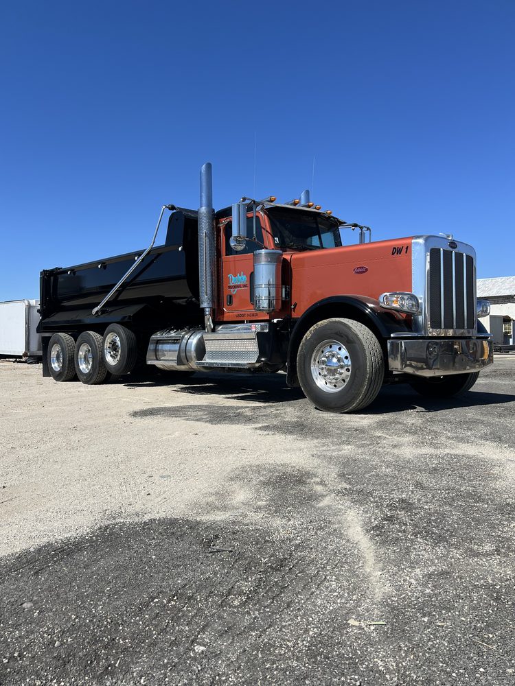 Orange Peterbilt with a dump body in the yard