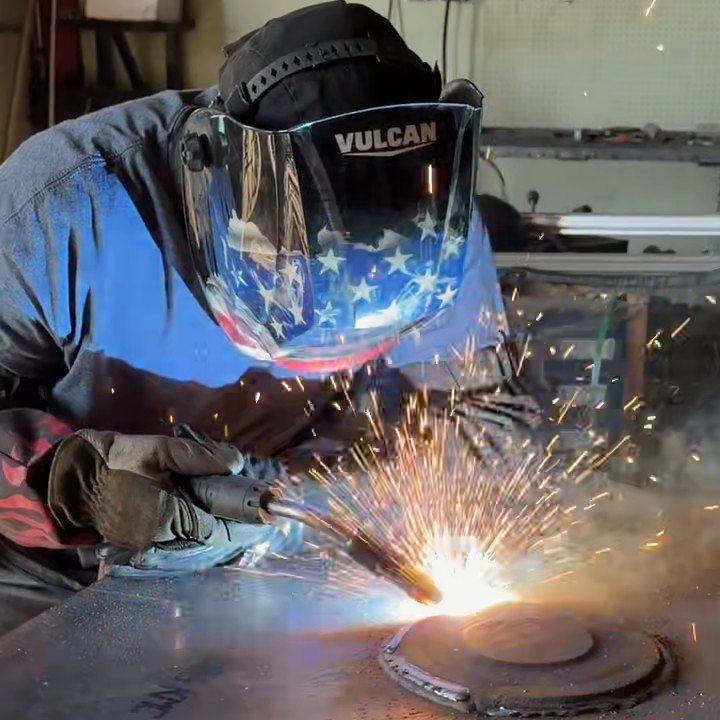 A DM Welding welder MIG welds a round plate onto a steel table top inside our Lancaster shop