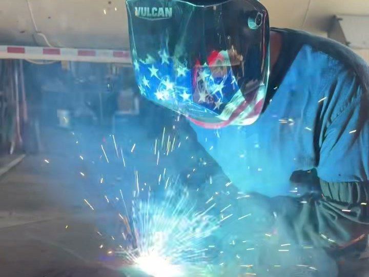 A DM Welding welder MIG welds a round plate onto a steel table top at our Lancaster shop on Division Street