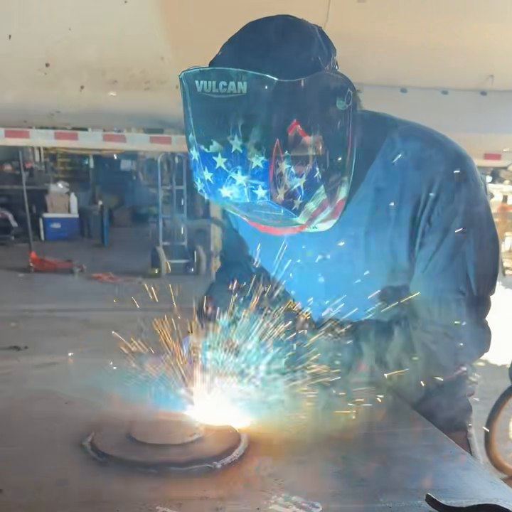 A DM Welding welder MIG welds a round steel plate onto a larger plate at our Lancaster shop on Division Street