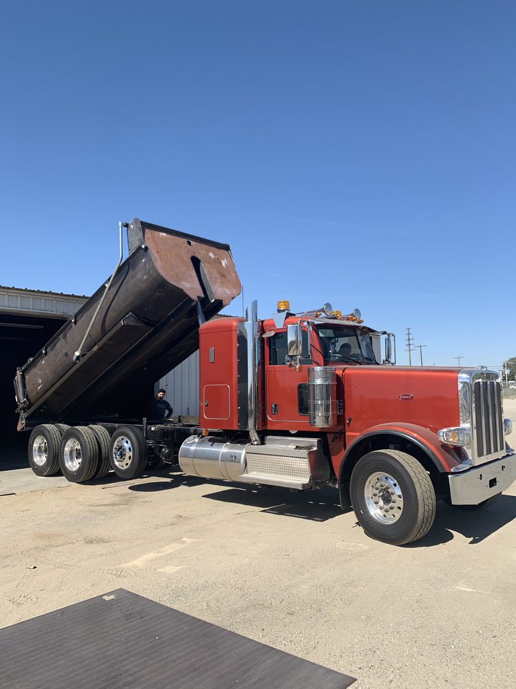 Black dump body raised on a red truck