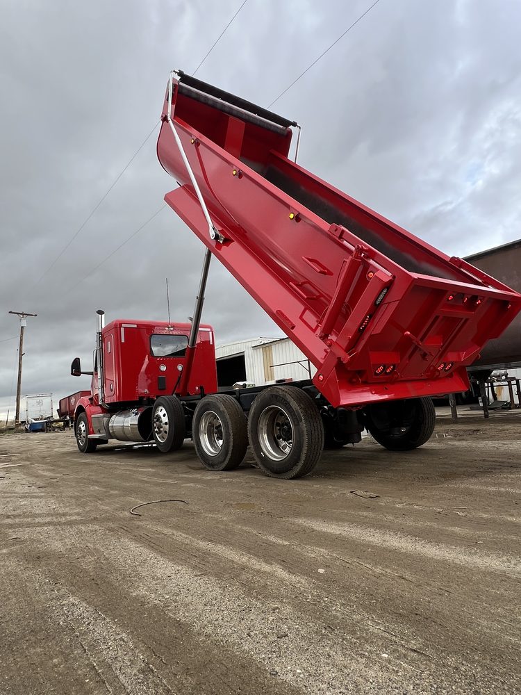 Red dump body raised to full tip