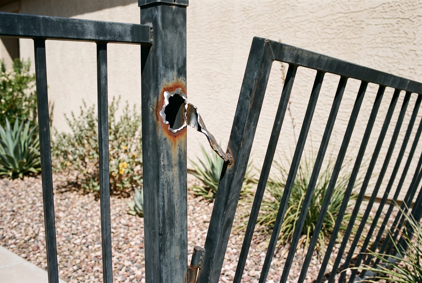 Design rendering of a hinge tab torn out of the thin wall of a square steel gate post, leaving a ragged hole