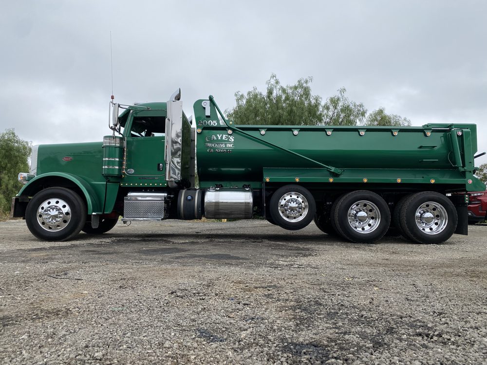 Full side view of a green Peterbilt and its dump body