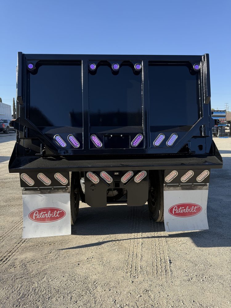Rear of a black dump body showing the tailgate and marker lights