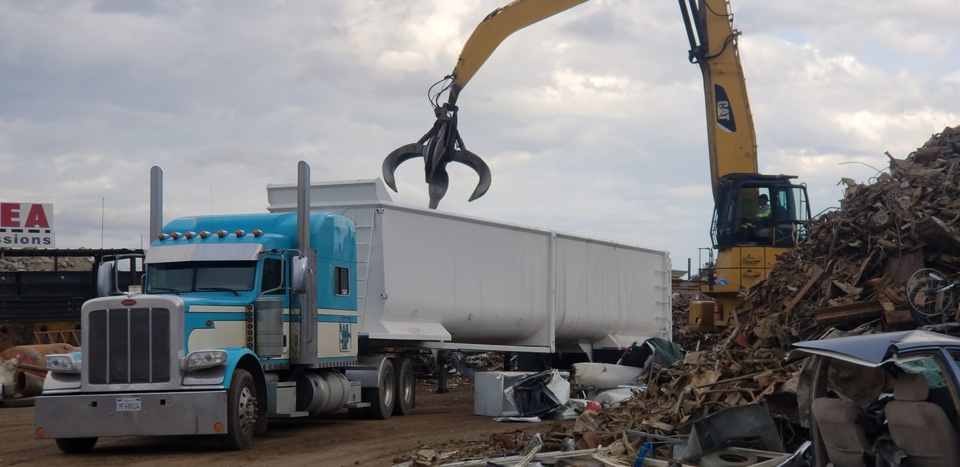 Transfer trailer being loaded by a grapple at a scrap yard